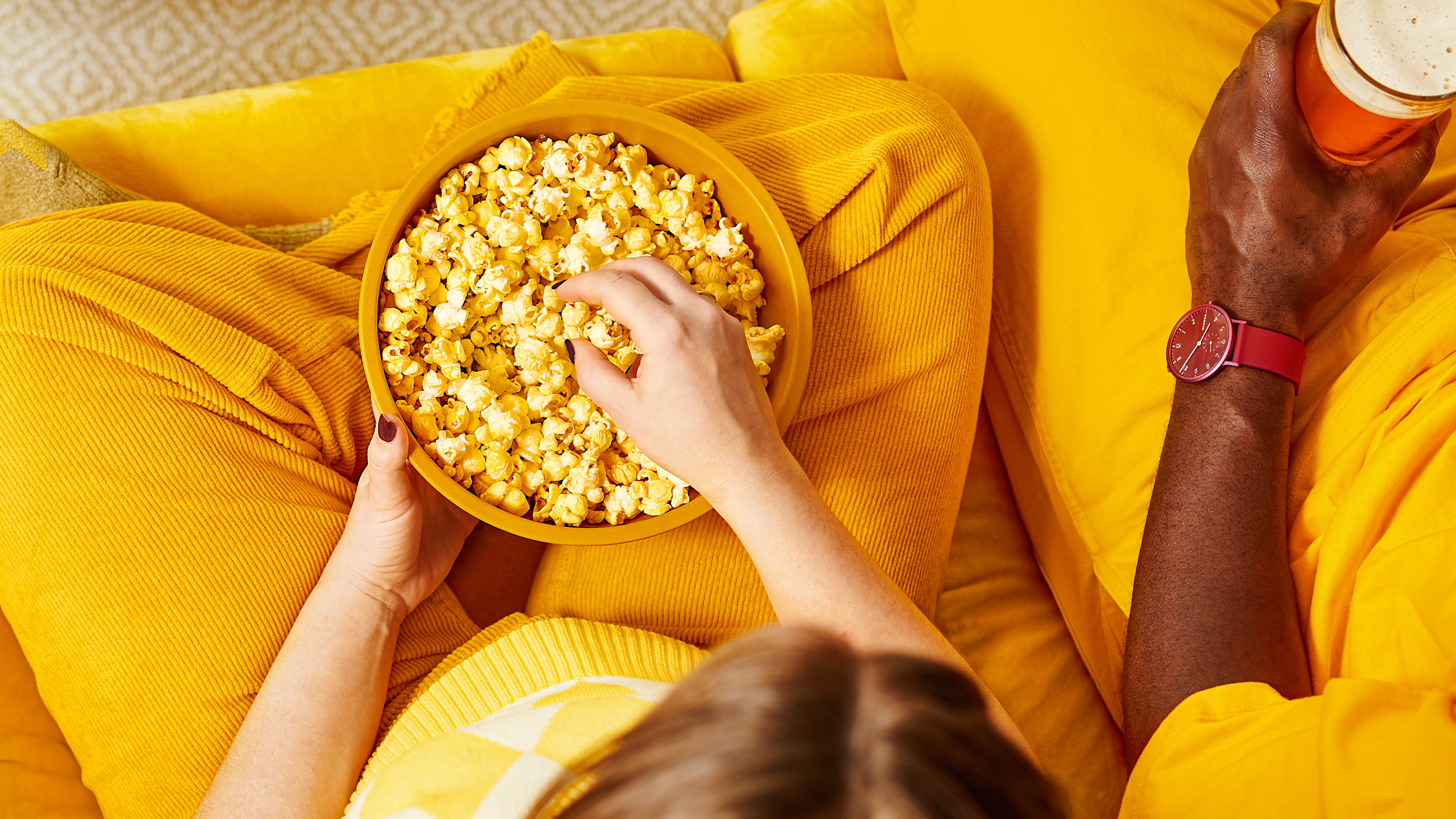 Two people eating bowl of magictime popcorn in yellow bowl with yellow attire.